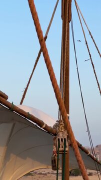 Traditional wooden boat pillar sailing canvas in Iran dhows lenj in Qeshm marine old sailor wear Arabian thobe climb sea navigate wind storm in Qatar rope the knot labor ocean maritime Persian Gulf