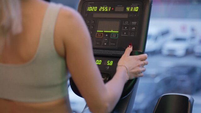 Over the Shoulder View of a Woman Adjusting Treadmill Display Speed