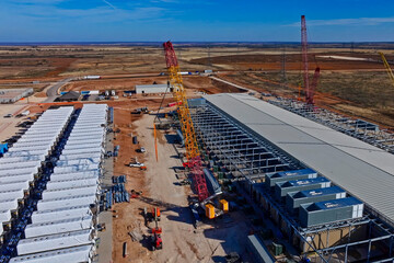Obraz premium Aerial view of data center construction with BESS batteries and red cranes