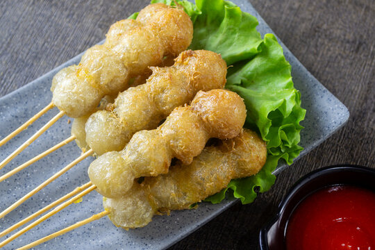 Cilor served on a plate, Cilor is a distinctive Indonesian street food consisting of aci (tapioca) skewers fried with egg, served with spicy chili sauce.