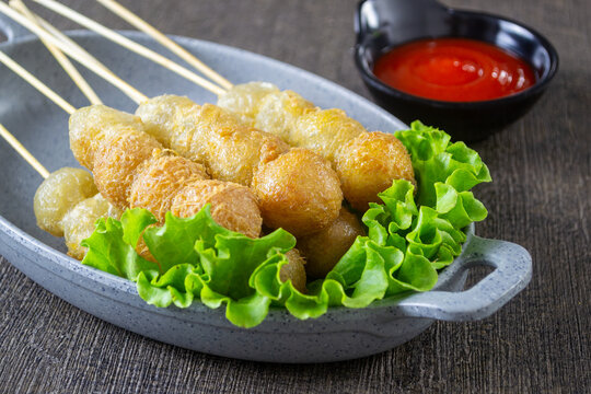 Cilor served on a plate, Cilor is a distinctive Indonesian street food consisting of aci (tapioca) skewers fried with egg, served with spicy chili sauce.