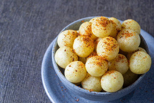 Chewy and delicious Indonesian street food Cimol Kentang served in a grey bowl sprinkled with spicy chili powder