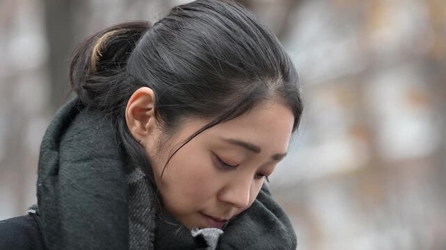 冬の屋外でマフラーを巻く30代の日本人女性