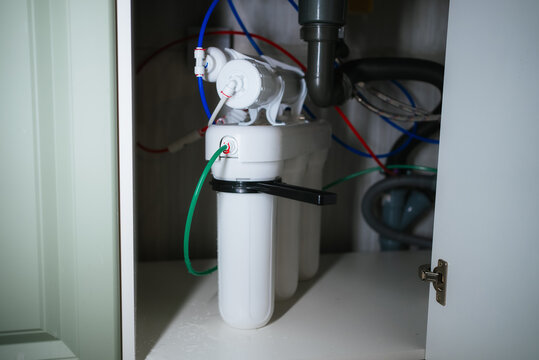 Reverse osmosis water purification system with visible filter cartridges and a network of colored tubing installed under a kitchen sink, providing filtered and clean drinking water