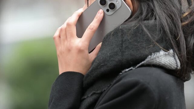 冬の屋外でスマートフォンで通話する30代の日本人女性