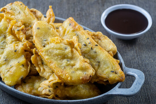 Pisang Goreng Wijen, Crispy Indonesian banana fritters with sesame seeds served in a grey oval plate with chocolate dipping sauce