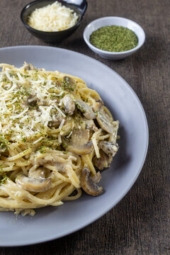 Creamy Italian spaghetti carbonara with sliced mushrooms, minced meat, grated cheese and dried parsley perfectly styled for restaurant menu