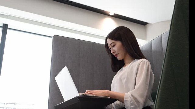 コワーキングスペースでノートパソコンを使って仕事をする20代の日本人女性