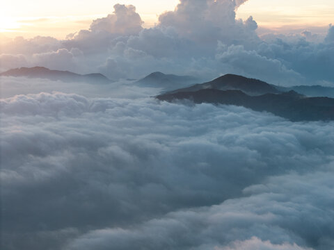 Aerial view of the mountainous landscape near Basecamp Gunung Bismo via Sikunang, with rolling peaks emerging from a thick sea of clouds in Kecamatan Kejajar, Jawa Tengah, Indonesia.