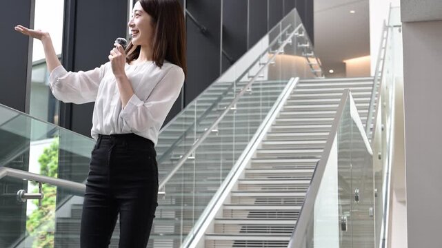 ピンマイクを持って歩きながらプレゼンテーションをする20代の日本人女性