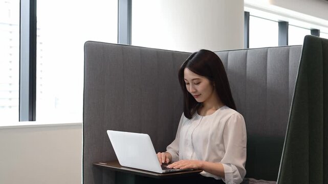 コワーキングスペースでノートパソコンを使って仕事をする20代の日本人女性