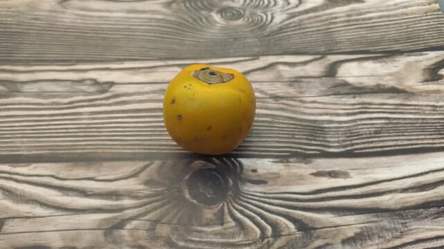 A fresh persimmon or Diospyros kaki on a wooden table