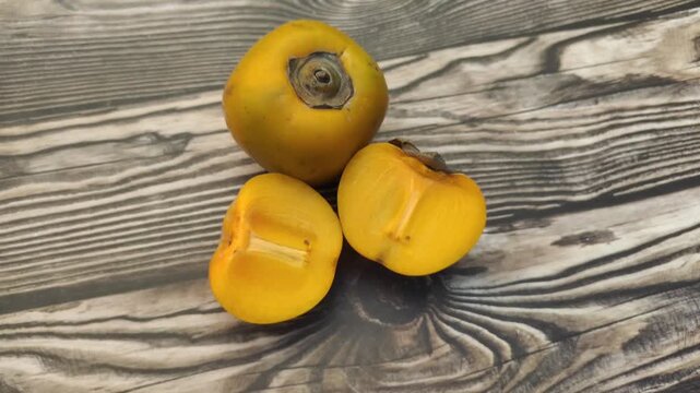 A fresh persimmon or Diospyros kaki on a wooden table