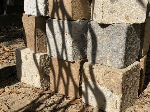 A stack of rough-hewn stones and bricks lies on the ground outdoors.
