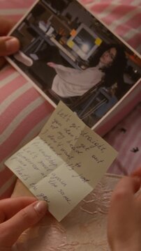 Vertical video of hands of multiethnic teenage girls holding printed photograph of love crush and reading handwritten letter. Romantic drama, relationship storytelling, and youth lifestyle promos