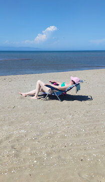 Woman enjoying a sunny day, lying on a beach chair by the sea