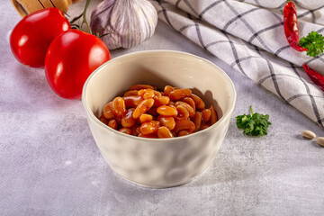Fototapeta premium Baked beans in a ceramic bowl with fresh tomato, garlic, and chili ingredients