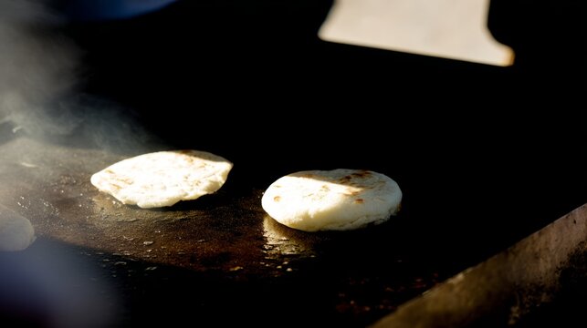 Arepas on cast-iron griddle beside cuatro guitar, tropical culinary and music scene.
