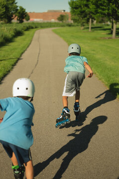 Two boys rollerblading on a path on a sunny day