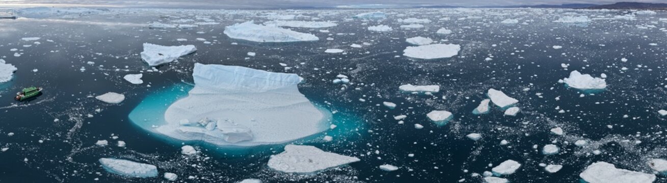 Small tour boat navigates through many icebergs