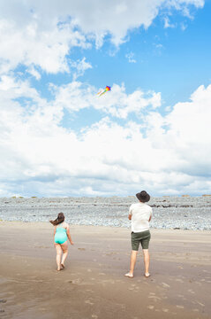 Father and daughter flying a colorful kite at the seaside