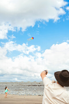 Man flying a colorful kite on a sandy beach