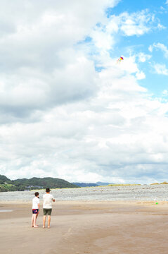 Father and son flying a kite on a sandy beach