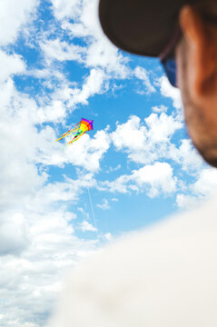 Man watching a colorful kite in a blue sky