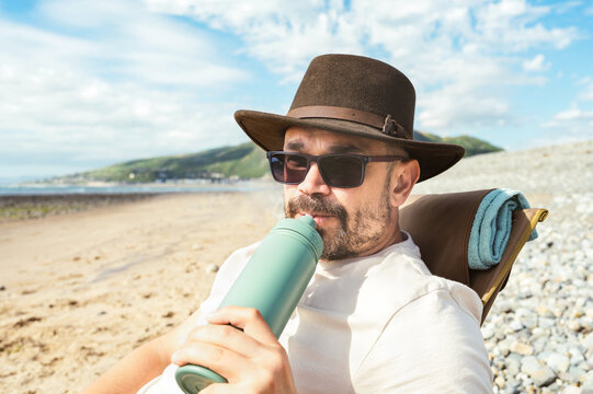 Man drinking from a reusable bottle while relaxing outdoors