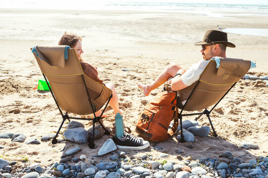 Couple relaxing in camping chairs on a sandy beach