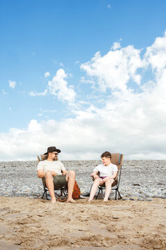 Father and teenager relaxing on camping chairs outdoors