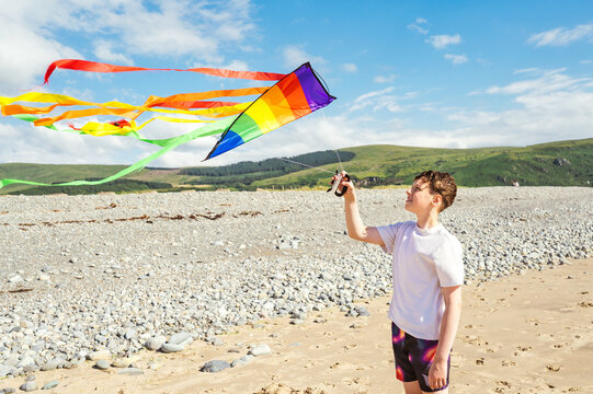 Teenager launching a colorful kite on the beach