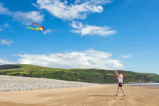 Teen boy flying a colorful kite on a sandy beach