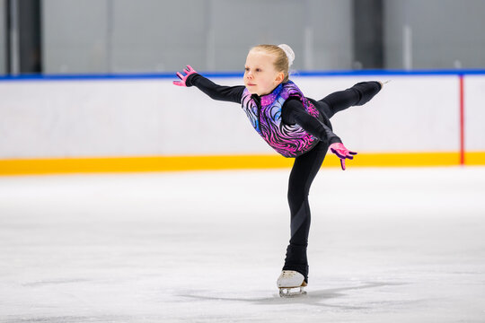 Focused young girl figure skating on an ice rink