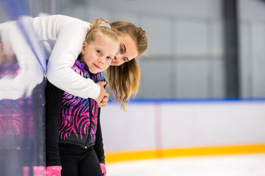 coach hugs a young athlete during an ice skating lesson.