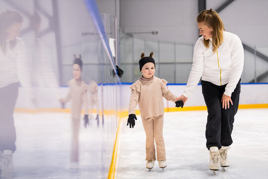 Mother teaches her young daughter to ice skate
