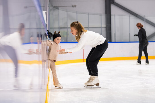 Little girl learning ice skating with professional coach at rink