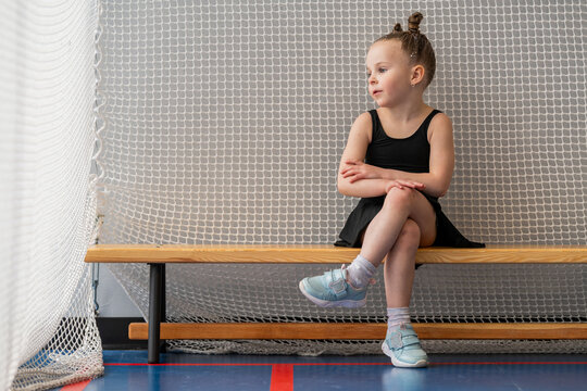 A little figure skater girl waits for training in the gym.