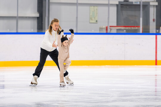 Woman teaching young child how to ice skate