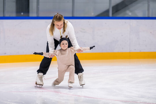 Skating coach helps a young girl on the ice