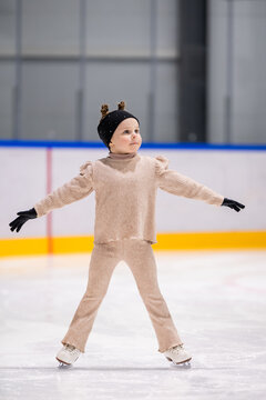 Adorable little girl practices ice skating on a rink
