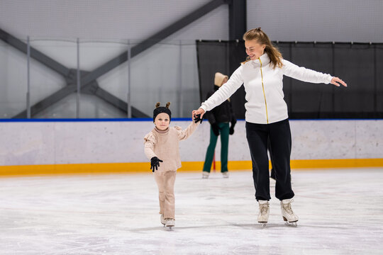 Woman teaches a little girl how to ice skate