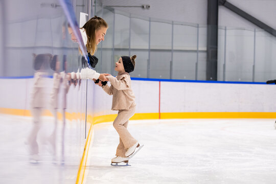 Little girl learning ice skating with professional coach at rink