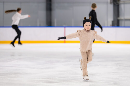 Little girl balances while ice skating on rink