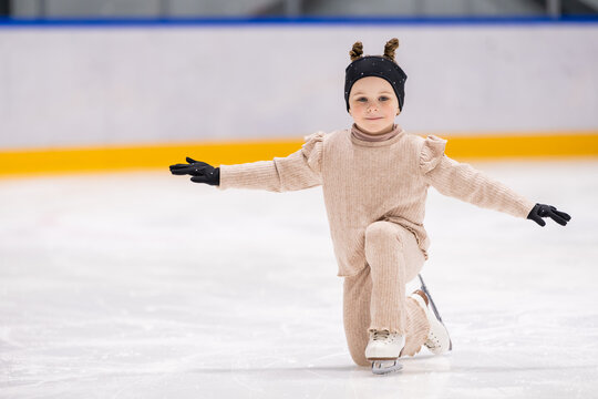 Happy little girl posing on one knee on ice rink
