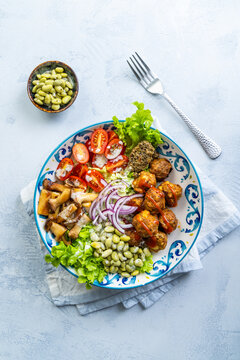 Hearty and healthy bowl with meatballs, mushrooms, beans, and fresh vegetables