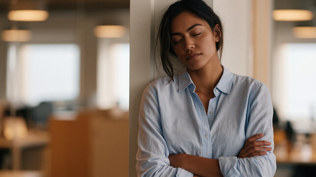 Pacific Islander empath in a crowded open-plan office pressing her back flat against a supply closet wall for a stolen quiet moment, eyes closed, arms crossed lightly over chest,