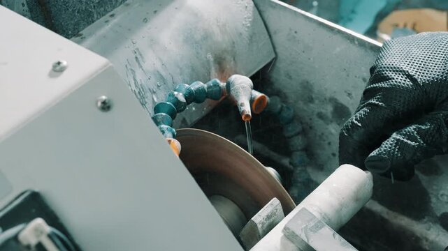 Close-Up of CNC Grinding Machine with Coolant and Operator's Gloved Hand
