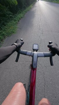View from cyclist's perspective on a road, showing handlebars, gloved hands, and GPS device under clear skies.