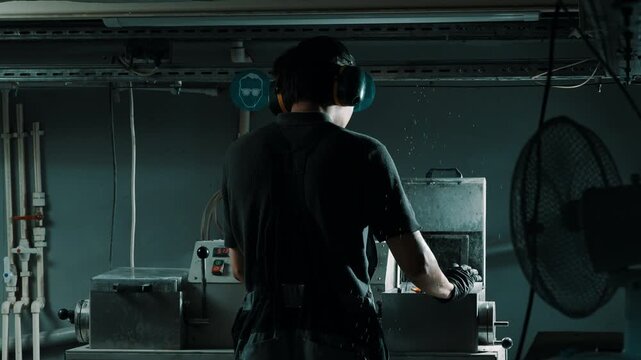 Factory worker operating industrial machine with ear protection